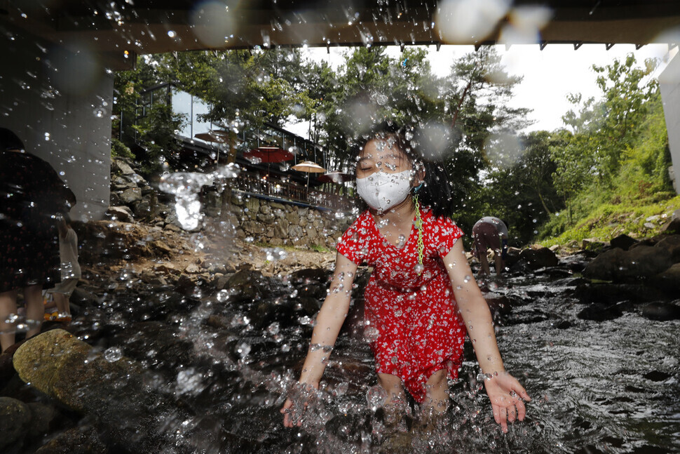A child splashes water toward the camera at a stream in Yongin, Gyeonggi Province, on Tuesday. (Lee Jeong-a/The Hankyoreh)