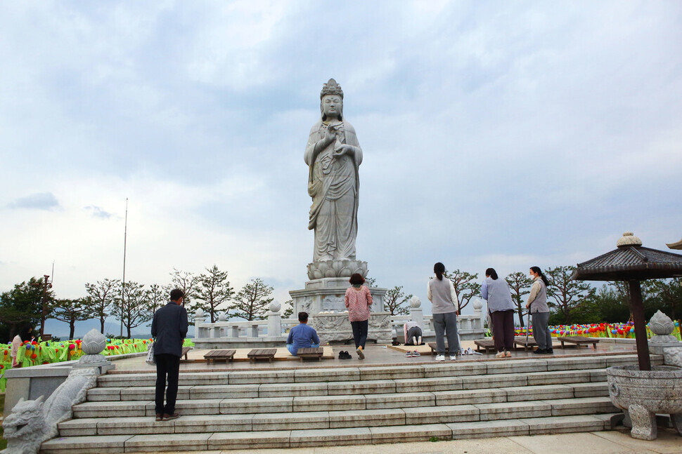 People pray in front of a Buddha statue that can be seen from Naksan Temple in Yangyang, Gangwon Province. (Her Yun-hee/The Hankyoreh)