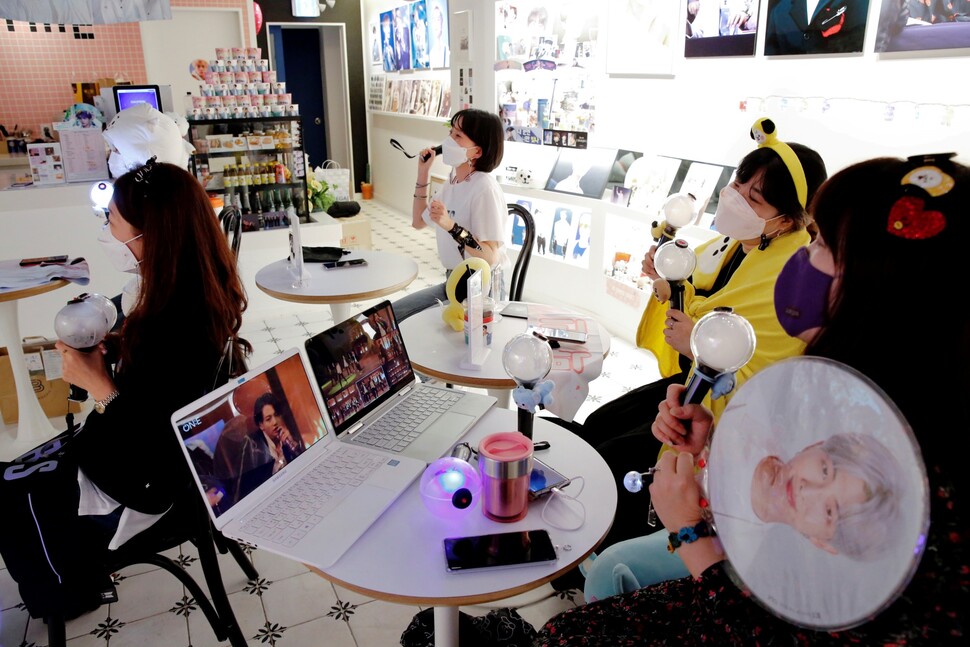2020년 10월 서울의 한 카페에서 케이팝 그룹 방탄소년단(BTS)의 팬들이 마스크를 쓴 채 온라인 스트리밍으로 중계되는 콘서트를 즐기고 있다. REUTERS 연합뉴스