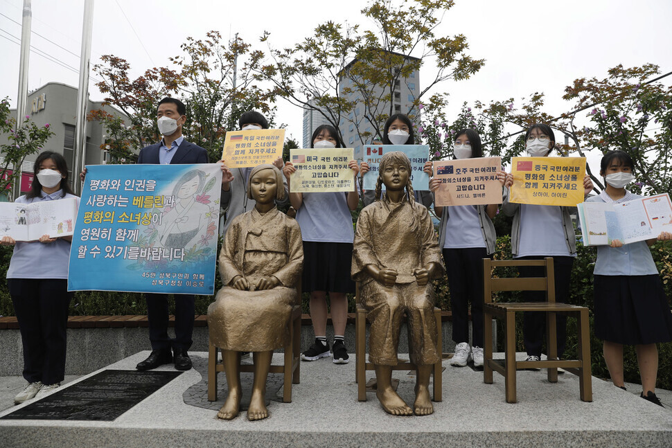 Seongbuk Mayor Lee Seung-roh and students from Gyesung High school hold a rally calling for the permanent preservation of a comfort woman statue in Berlin’s Mitte borough while standing behind comfort woman statues at the entrance of Hansung University Station in Seoul on Wednesday. (Lee Jeong-a/The Hankyoreh)