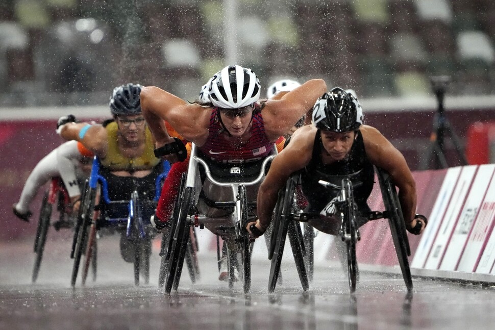 8월31일 일본 도쿄 국립경기장에서 열린 여자 육상 1500m(T54) 결승에 출전한 스위스의 마누엘라 셰어(맨 오른쪽)와 참가 선수들이 휠체어 바퀴에서 튕기는 빗방울을 뚫고 질주하고 있다.