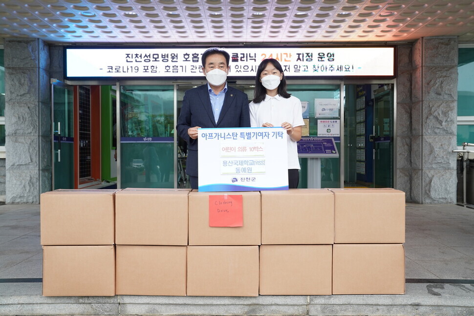 Emily Dhong, right, donates clothes she and her peers collected to Jincheon County Governor Song Ki-seop on Tuesday. (provided by Jincheon County)
