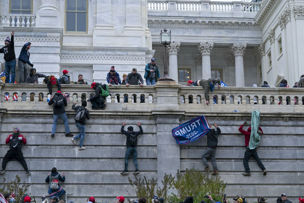 올해 1월6일 워싱턴 의사당에 난입한 트럼프 지지자들이 담장을 기어오르고 있다. AP 연합뉴스