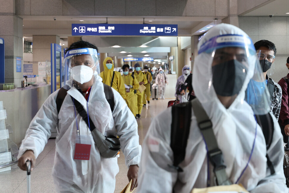 Travelers wearing personal protective clothing arrive at Incheon International Airport on Monday morning. (Yonhap News)