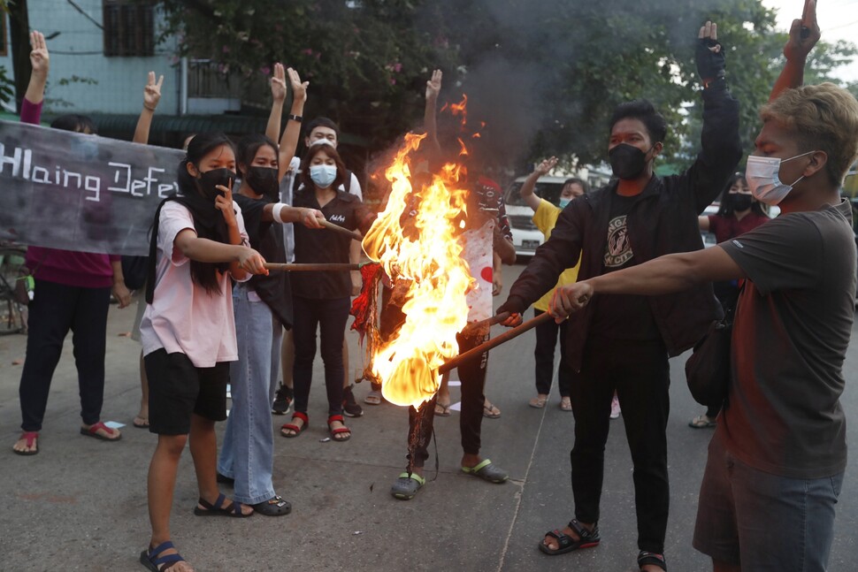 미얀마 시민들이 11월24일 양곤에서 기습시위를 벌이며 세 손가락을 든 채 미얀마 국기를 태우고 있다. 쿠데타 정권에 반대하는 시민들은 민주 진영이 세운 민족통합정부(NUG)를 지지하고 기존 미얀마 정부의 상징물을 인정하지 않는다.