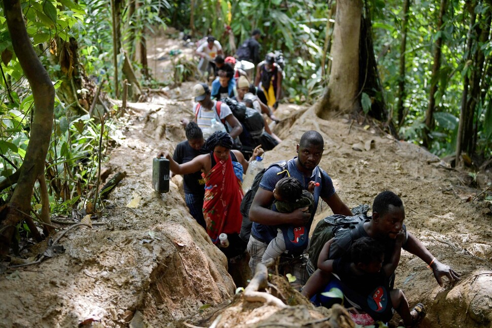 아이티 이주민들이 9월26일 아이들을 품에 안은 채 콜롬비아 초코 지역의 다리엔갭 밀림을 헤쳐나가고 있다. 이들은 파나마를 거쳐 미국으로 가는 길이다. 험한 협곡 지형의 이 밀림은 뱀과 마약조직이 자주 출몰하는 곳이다.