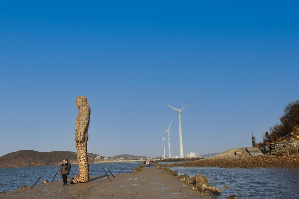 A person walks by a large art sculpture on the Tando ocean walkway. (Her Yun-hee/The Hankyoreh)