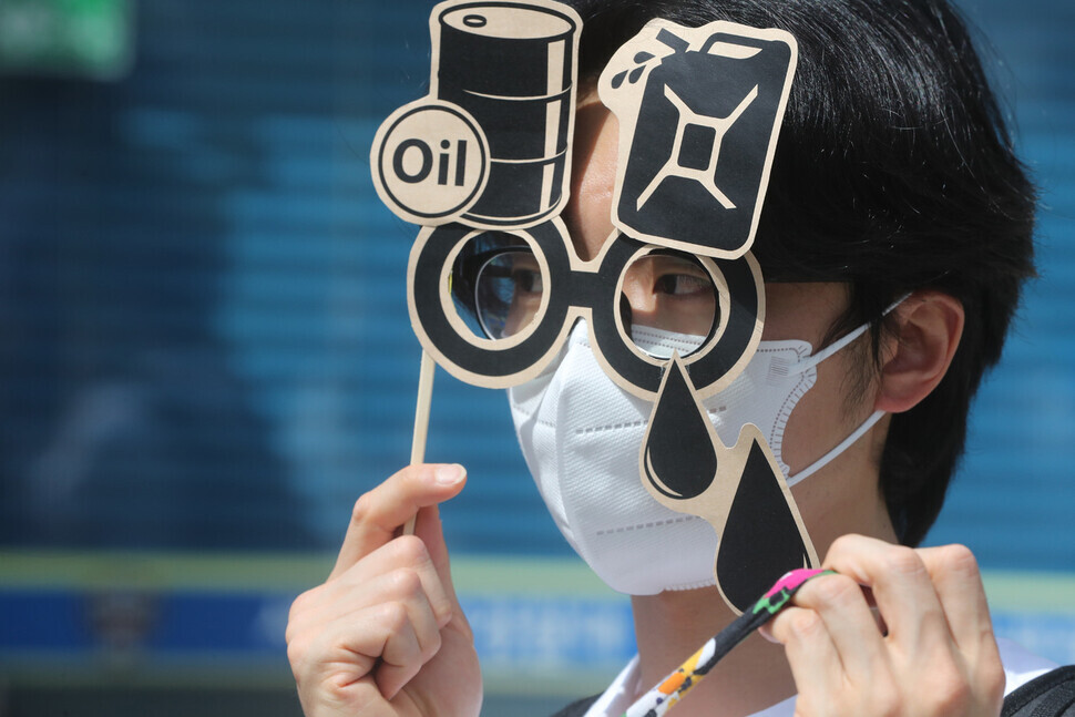 A participant in a press conference for the march holds up a mask picturing an oil barrel, a reference to oil leaks from the US military base. (Kim Tae-hyeong/The Hankyoreh)