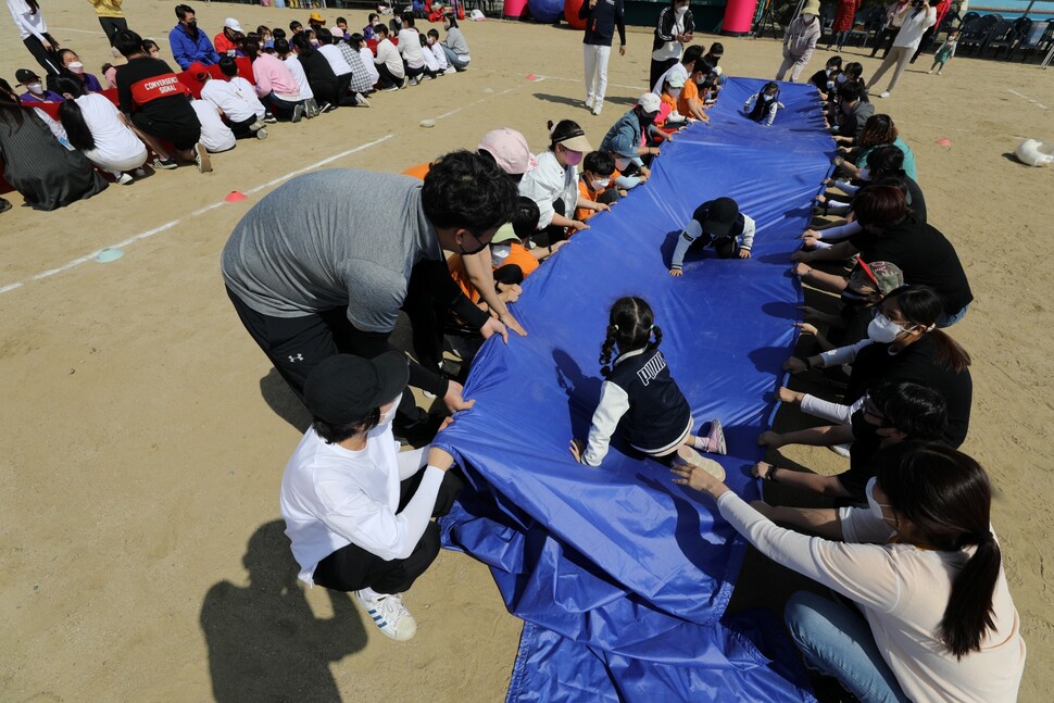 유치부 어린이들이 학부모와 초등학생들이 펼친 천 위를 통과하고 있다.