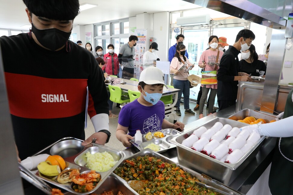 운동회에 참가한 학부모와 학생들이 식판에 음식을 받고 있다. 학부모들은 점심 식사 뒤 급식을 평가하는 설문조사에 참여했다.