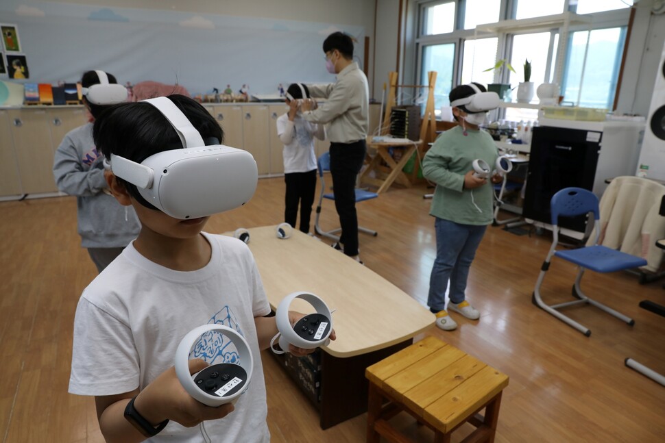 어린이들이 송근상 선생님의 설명을 들으며 가상현실(VR) 게임을 즐기고 있다.