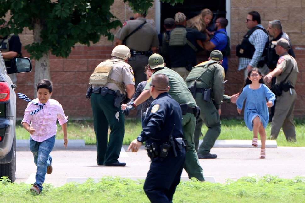 18살 고교생 살바도르 라모스가 5월24일(현지시각) 미국 텍사스주 유밸디의 롭초등학교에 난입해 총기를 난사하자 학생들이 창문을 넘어 달아나고 있다. 출동한 경찰이 학생들의 피신을 돕고 있다.