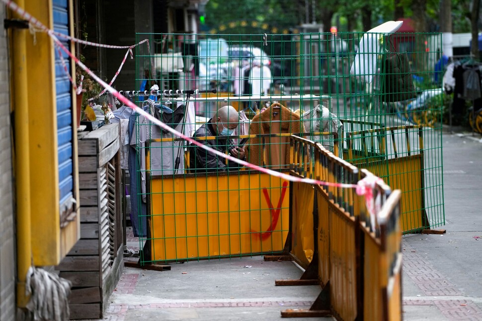 2022년 5월 중국 베이징의 철조망으로 싸인 차단막 안에서 시민이 휴대전화를 보고 있다. REUTERS