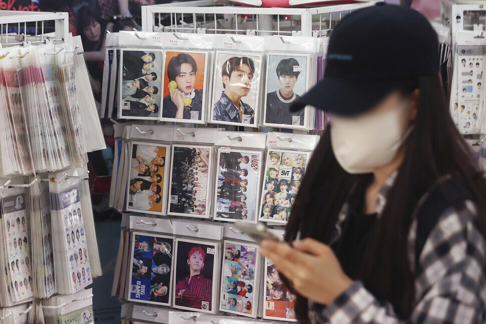 A person walks by a shop selling items with K-pop artists’ photos printed on them in the Myeongdong shopping district of Seoul on June 15. (Yonhap News)