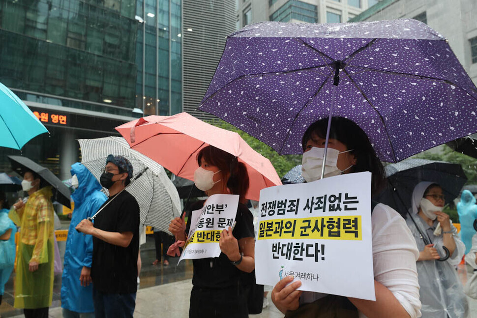 Participants in the 1,550th Wednesday Demonstration calling for the resolution of the issue of wartime sexual slavery by the Japanese military stand in the rain outside the former Japanese Embassy in downtown Seoul on June 29, denouncing military cooperation with Japan. (Kim Jung-hyo/The Hankyoreh)