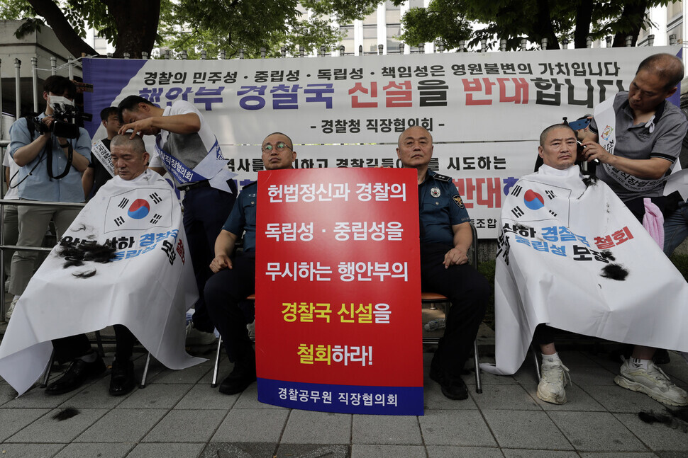 Leaders of regional police associations have their heads shaved outside the National Police Agency’s headquarters on July 4 as they hold up a sign calling for the repeal of a Ministry of Interior and Safety policy that would establish a police affairs bureau. (Kim Myoung-jin/The Hankyoreh)