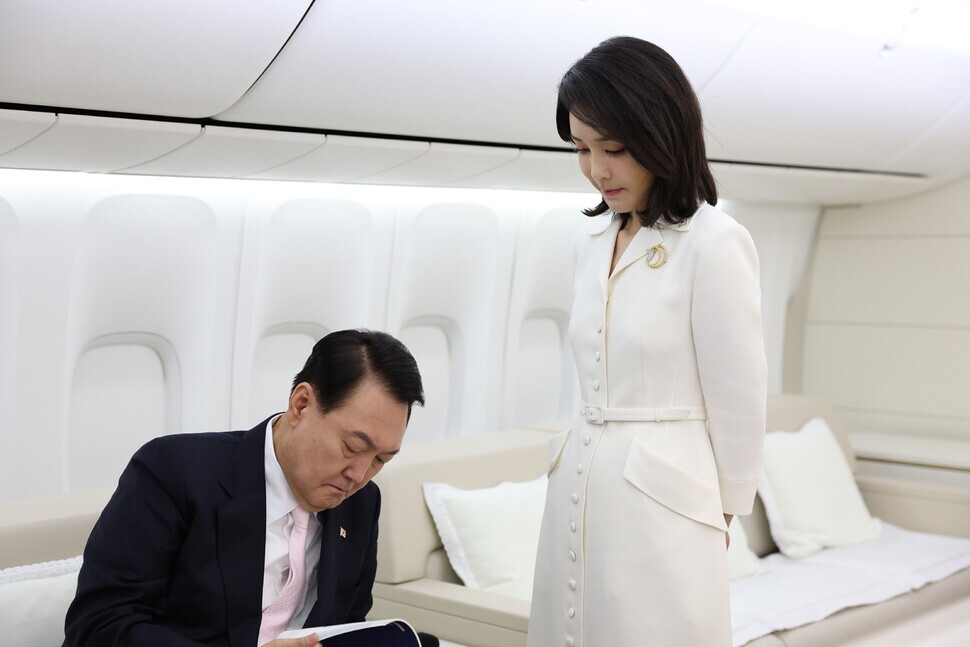 First lady Kim Keon-hee stands over President Yoon Suk-yeol as he reviews material aboard the presidential jet headed to Madrid for the NATO summit on June 27. (provided by the presidential office)