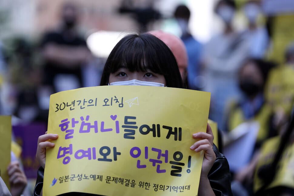 A participant in the 1,562nd Wednesday Demonstration in Seoul holds up a sign calling for honor and human rights to be afforded to the aging survivors of Japan’s wartime system of sexual slavery on Sept. 21.
