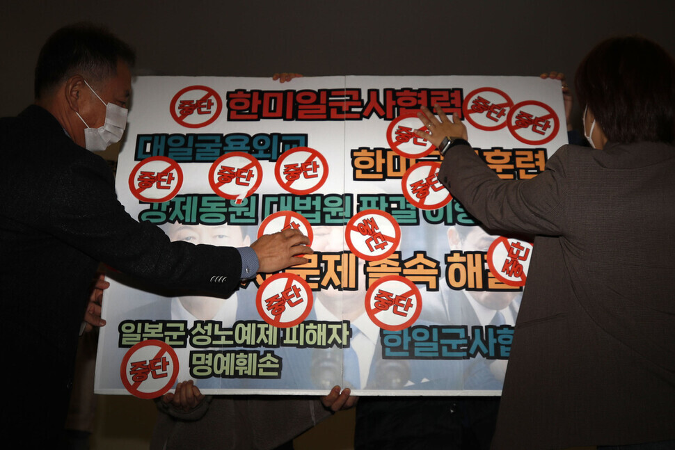 Participants in a joint press conference marking the fourth anniversary of the Supreme Court ruling ordering Japan to compensate Korean victims of Japan’s forced labor mobilization place stickers reading “END” on a sign reading various things including “South Korea-US-Japan military cooperation.” (Kim Hye-yun/The Hankyoreh)