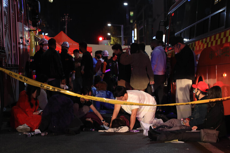 In the early hours of Oct. 30, bystanders keep an eye on victims of the crowd crush as they wait to be transported to the hospital. (Park Jong-shik/The Hankyoreh)