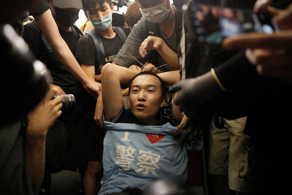 푸궈하오가 2019년 8월13일 홍콩의 첵랍콕 국제공항에서 반중 시위대에 둘러싸여 있다. 중국 관영매체 &lt;환구시보&gt; 기자로 취재를 나온 그는 “홍콩 경찰을 사랑한다”는 티셔츠를 가지고 있다가 시위대로부터 폭행을 당했다. 연합뉴스