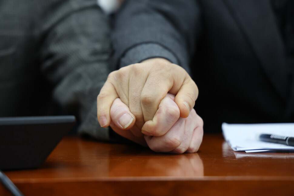 Two individuals who each lost a loved one in the tragic Itaewon crowd crush of Oct. 29 hold one another’s hand during a roundtable between lawmakers and bereaved families at the National Assembly in Seoul on Dec. 1. (Yonhap)
