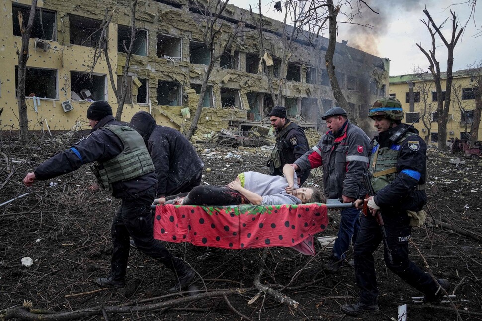 러시아군이 2022년 3월9일(현지시각) 우크라이나 마리우폴의 산부인과 병원을 폭격해 중상을 입은 임신부를 응급구조대원과 자원봉사자가 옮기고 있다. 이 임신부는 다른 병원으로 옮겨졌지만 결국 숨을 거뒀다.