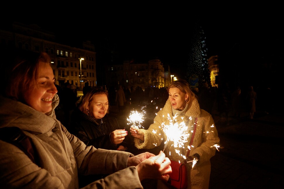 우크라이나 키이우 시민들이 2022년 12월31일 러시아군 공습에 대비해 소등하기 직전 새해를 축하하는 폭죽에 불을 붙이고 있다.