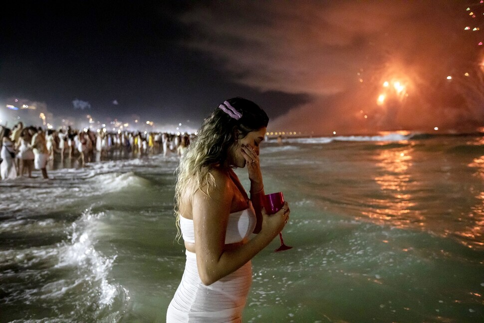 새해를 축하하는 불꽃놀이가 펼쳐진 브라질 리우데자네이루 코파카바나 해변에서 한 여성이 축배를 든 채 눈물을 흘리고 있다.