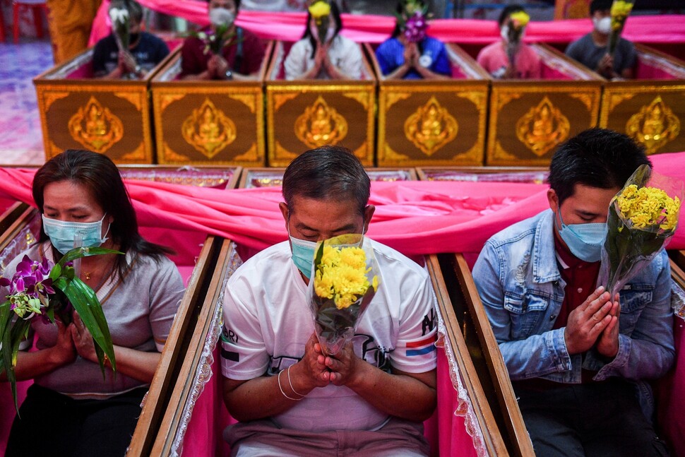 타이 방콕 외곽의 논타부리 사원에서 1월2일 불자들이 관 속에 들어가 꽃을 든 채 합장하고 있다. 이는 액운을 쫓고 새로 태어나기 위한 의식이다.