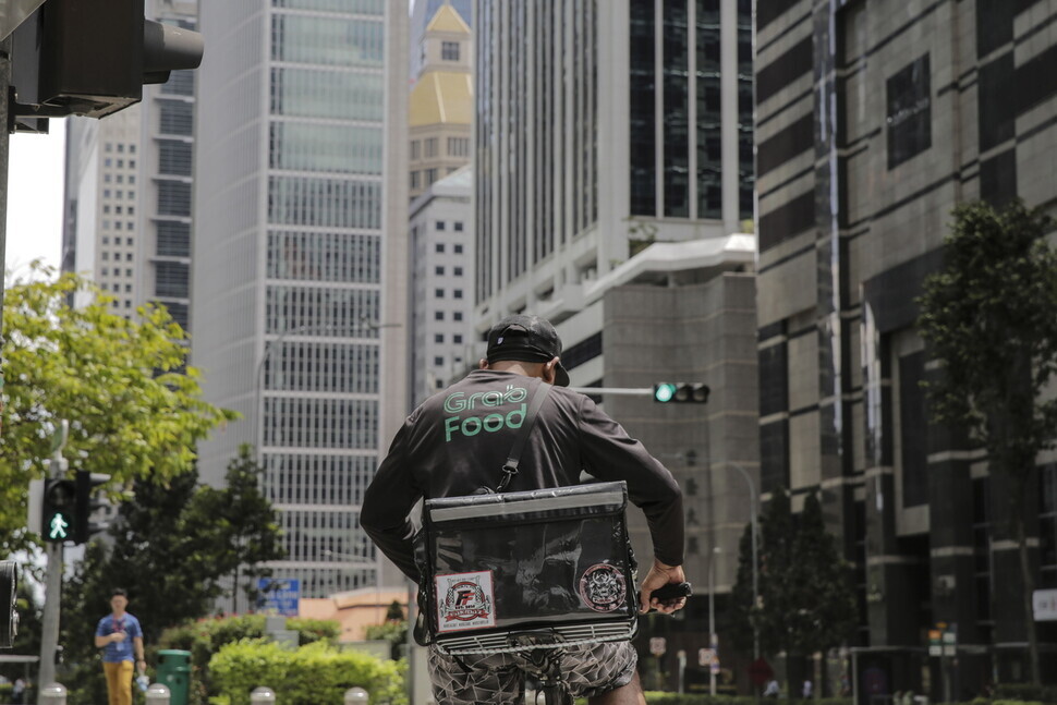 A rider with the delivery platform Grab waist for a light on a street in Singapore’s financial district in 2020. (EPA/Yonhap)