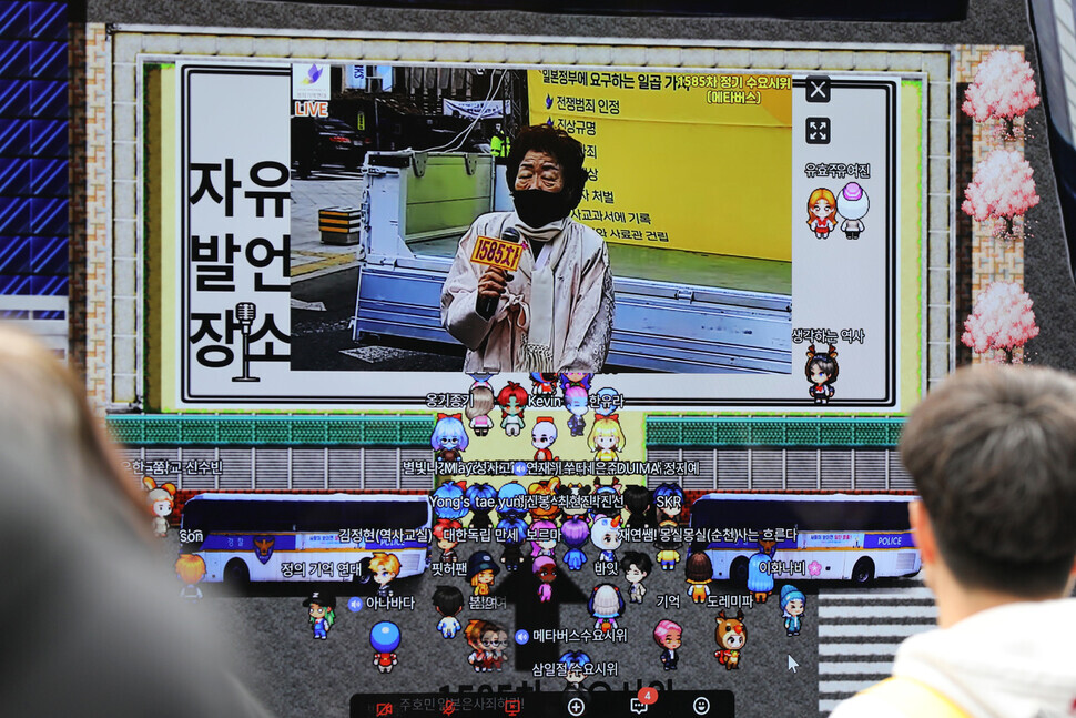 Lee Yong-soo, a survivor of Japan’s “comfort women” system of sexual slavery, speaks at the 1,585th Wednesday Demonstration held near the former Japanese Embassy in Seoul on March 1, shown on a screen connected to a metaverse app. (Kim Hye-yun/The Hankyoreh)