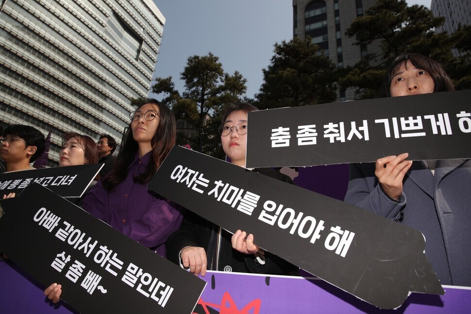 hose present at the press conference hold up signs with various phrases based on looks-based workplace harassment on them. (Kim Bong-gyu/The Hankyoreh)