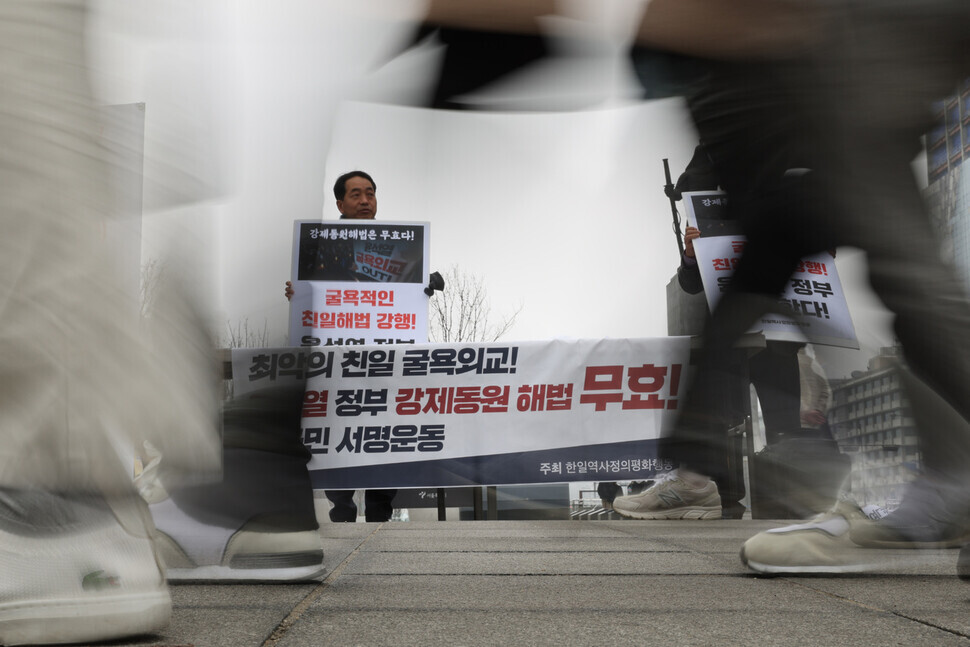 An activist with Joint Action for Historical Justice and Peaceful Korea-Japan Relations holds up a sign asking for passersby to sign their campaign to void the Yoon Suk-yeol administration’s proposed plan for compensating victims of Japan’s forced labor mobilization. (Kim Hye-yun/The Hankyoreh)