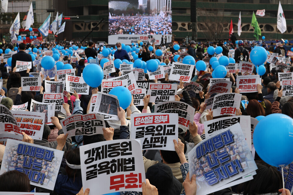 Participants in a nationwide rally on March 11 condemn Seoul’s “degrading” solution to forced mobilization compensation and call for an apology and compensation by Japan hold up signs in Seoul Plaza. (Kim Hye-yun/The Hankyoreh)