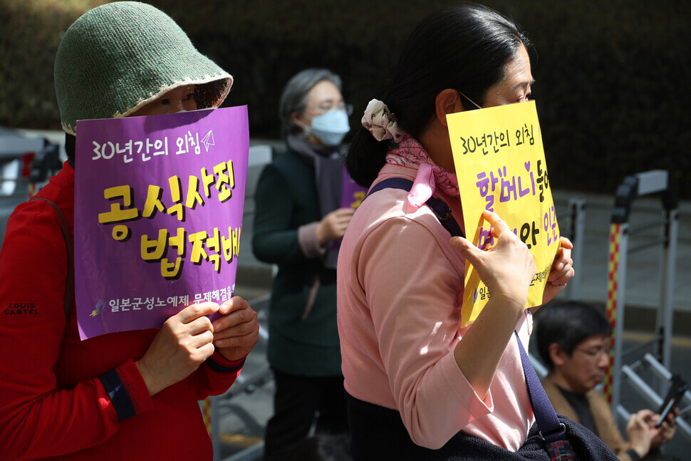Participants at the 1,588th Wednesday Demonstration on March 22 hold up signs demanding a formal apology and legal reparations from Japan. (Kang Chang-kwang/The Hankyoreh)