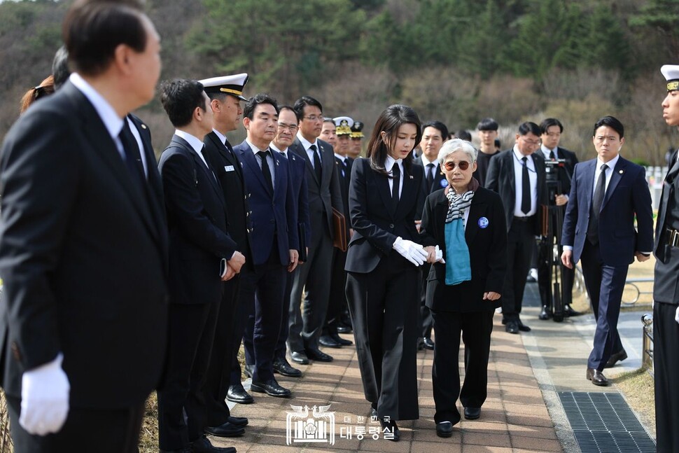 2023년 3월24일 천안함 용사 묘역에서 김건희 여사가 한 희생자의 가족과 함께 걷는 모습을 윤 대통령이 지켜보고 있다. 대통령실