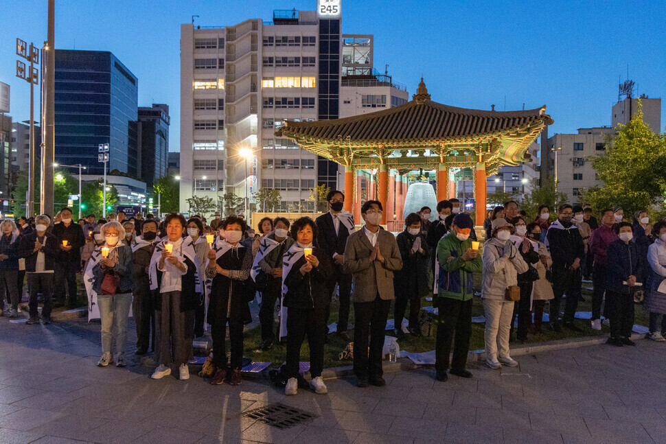 Participants in the May 1 prayer meeting by the CPAJ in Gwangju pray in front of the Gwangju Democracy Bell while holding candles. (Park Seung-hwa/The Hankyoreh)