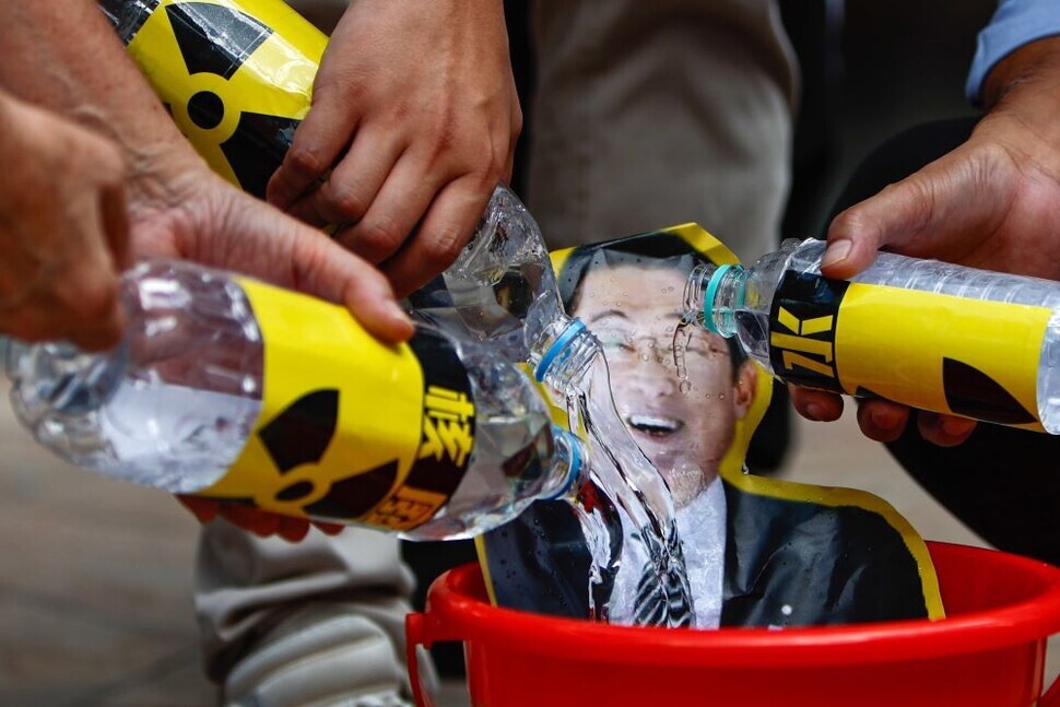 At an Aug. 23 protest of Japan’s plan to dump contaminated water from the Fukushima nuclear plant into the ocean, Hong Kong fishers pour water marked “nuclear wastewater” onto a photo of Japanese Prime Minister Fumio Kishida. (EPA/Yonhap)