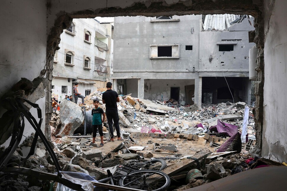 Locals in Rafah, in southern Gaza, survey the damage to buildings caused by Israeli air strikes on Oct. 12. (AFP/Yonhap)