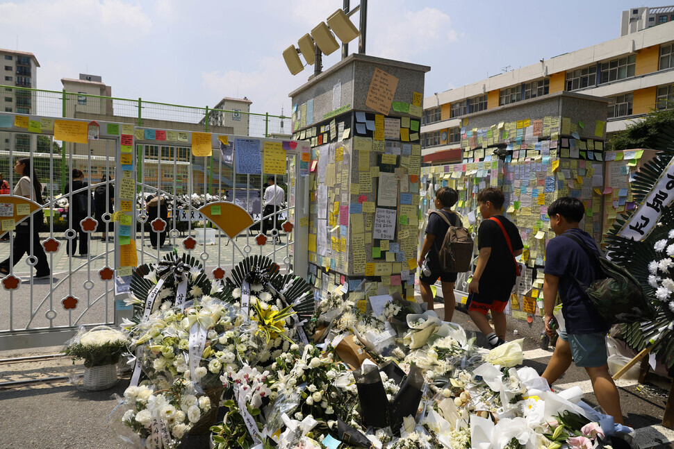 Flowers and messages crowd the main gate of an elementary school in Seoul’s Seocho District on July 18 after a teacher was found dead in the school after taking her life. (Yoon Woon-sik/The Hankyoreh)