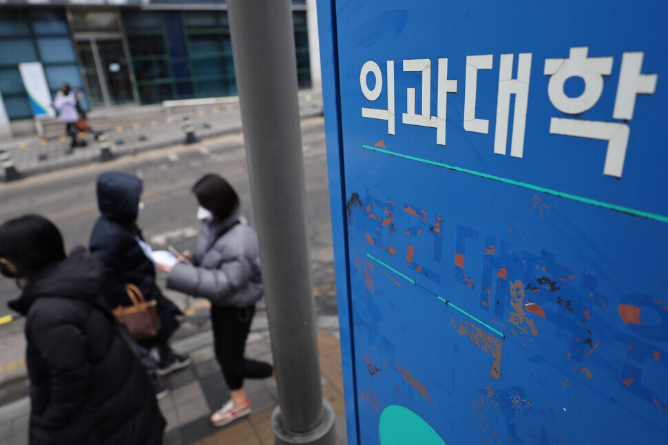People walk past the sign for a medical school in Seoul on March 6, 2024. (Yonhap)