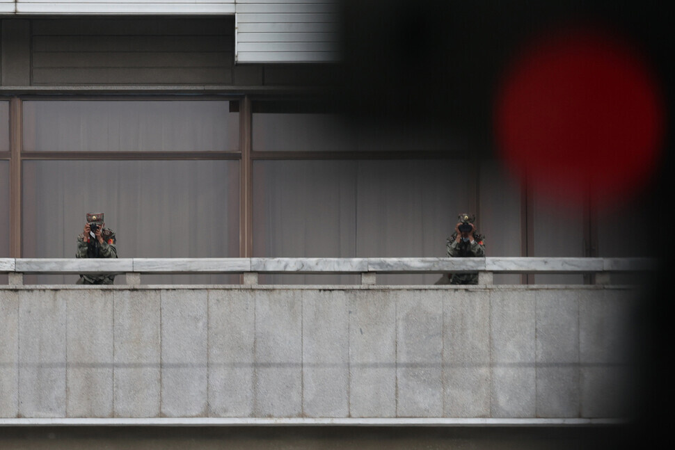 North Korean soldiers with a camera and binoculars peer over the balcony of Panmungak at the JSA. (Kim Hye-yun/The Hankyoreh)