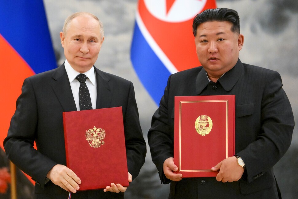 Russian President Vladimir Putin (left) and North Korean leader Kim Jong-un stand for a photo with copies of their newly signed pact establishing a comprehensive strategic partnership between their two nations following their summit in Pyongyang, North Korea, on June 19, 2024. (AP/Yonhap)