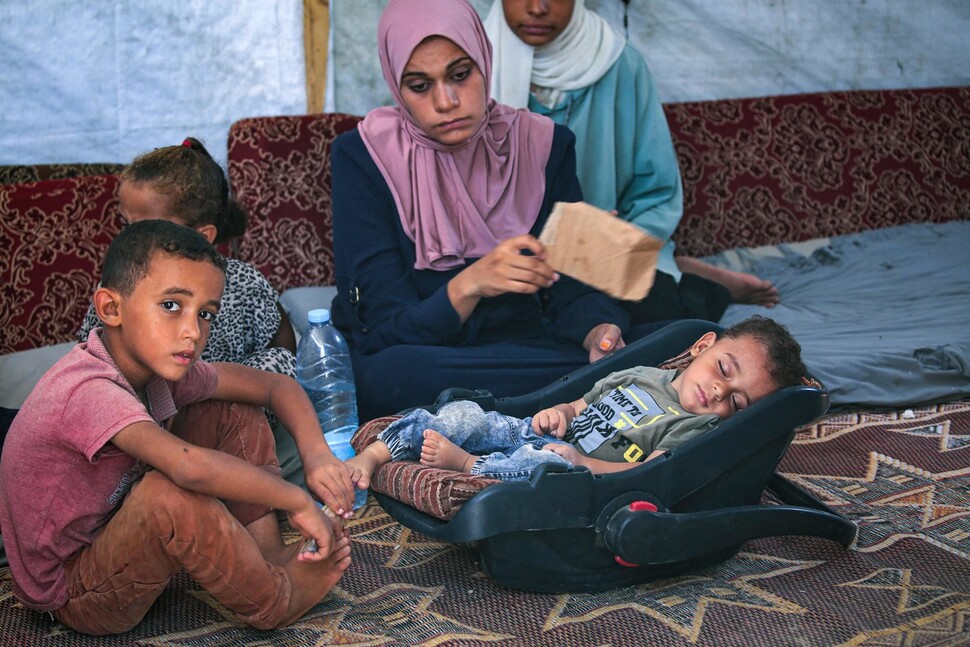 Abd al-Rahman Abu al-Jidyan, uma criança de 10 meses com poliomielite, dorme rodeado pela sua família numa tenda improvisada em Deir al-Balkh, no centro da Faixa de Gaza. Deir Balkh/AFP Yonhap