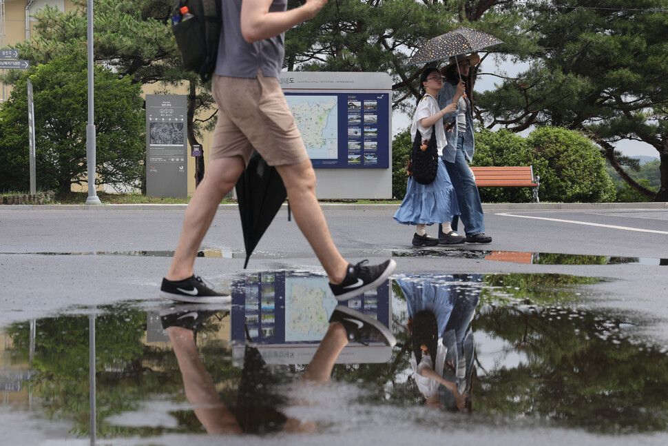 지난 1일 경기도 파주시 임진각에서 관광객들이 양산과 우산을 든 채 장맛비로 젖은 땅을 걷고 있다. 연합뉴스