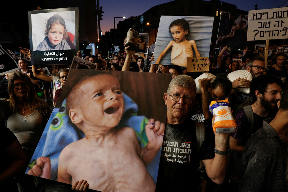 2025년 7월22일 이스라엘 텔아비브에서 열린 반전집회에서 참가자들이 한 손에는 굶주린 팔레스타인 땅 가자지구 어린이 사진을, 다른 손에는 밀가루를 들고 시위를 벌이고 있다. REUTERS 연합뉴스
