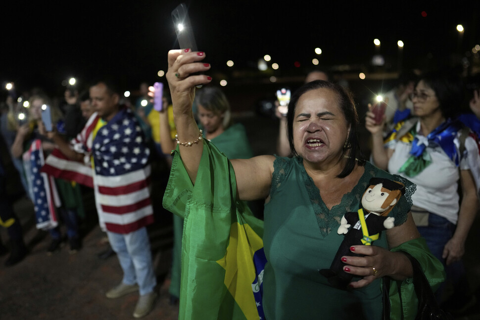 2025년 9월11일 브라질 수도 브라질리아에서 자이르 보우소나루 전 대통령 지지자들이 브라질 국기와 성조기를 두른 채 야간집회를 하고 있다. AP 연합뉴스