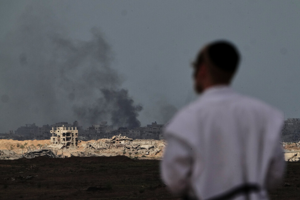 이스라엘과 하마스가 도널드 트럼프 미국 대통령이 제안한 평화구상 1단계에 합의했다는 발표가 나온 뒤인 2025년 10월9일 한 유대인 남성이 멀리 팔레스타인 땅 가자지구에서 폭발로 검은 연기가 치솟는 모습을 지켜보고 있다. AP 연합뉴스