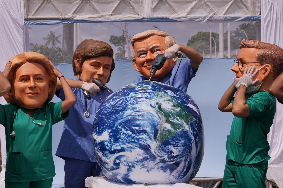 20일(현지시각) 브라질 벨렝에서 하비에르 밀레이 아르헨티나 대통령(왼쪽 둘째)과 도널드 트럼프 미국 대통령(왼쪽 셋째) 가면을 쓴 시위 참가자들이 지구를 시추하는 행위극을 하고 있다. 벨렝/AP 연합뉴스